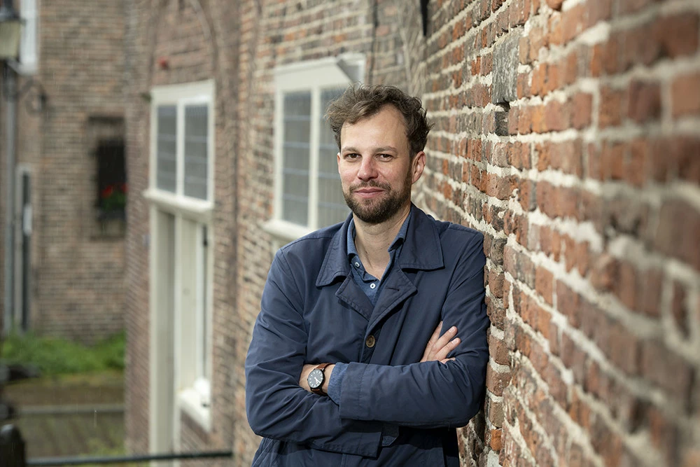 Steven Lenselink leunt tegen een oude bakstenen muur in het oude centrum van Amersfoort