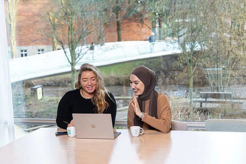 Babet van den Broek, teamleider Migratie en Inburgering, en Emina Sutovic, beleidsadviseur Migratie, zitten naast elkaar aan een tafel